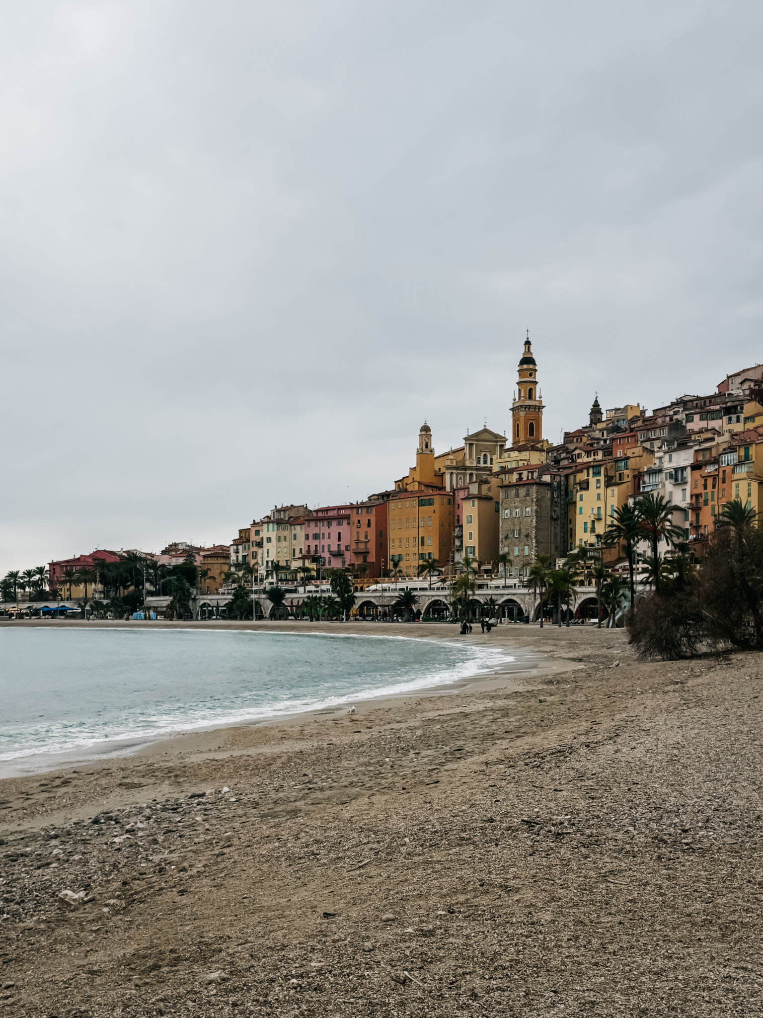 Praia de menton com casas coloridas ao fundo