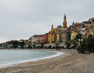 Praia de menton com casas coloridas ao fundo